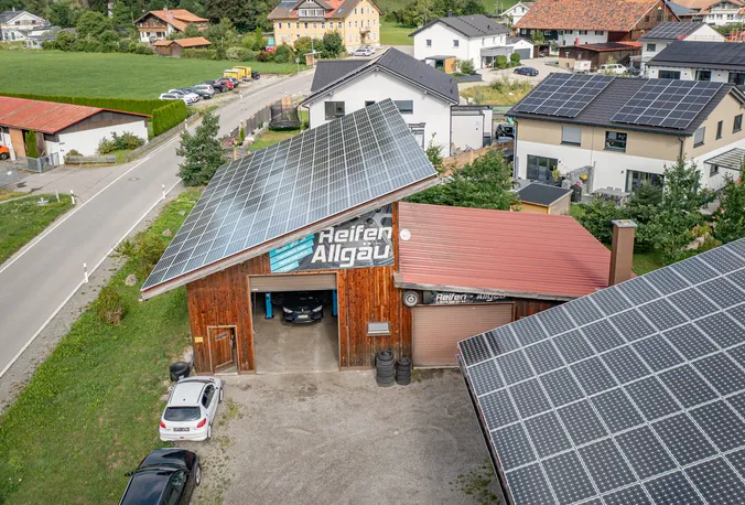 Luftaufnahme des Betriebs von Reifen Allgäu mit Photovoltaikdächern, davor die Straße und die Häuser von Immenstadt